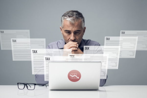 A man looks at a computer while envisioning tax forms
