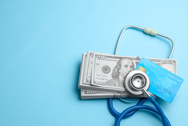 Stack of cash dollars and credit card with stethoscope on blue background. The concept of medical strechevka or expensive medicine, doctors salary.
