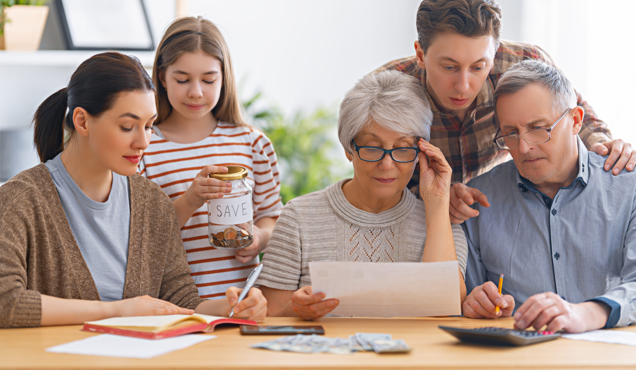 Family sitting at a desk with a paper receipt and calculating expenses, managing budget.