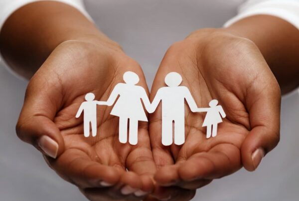 Open hands holding a paper cut out of a family